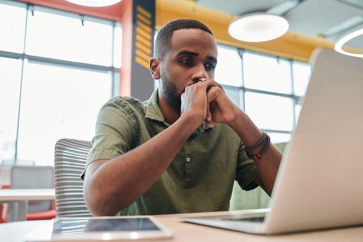 Un homme regarde son ordinateur portable avec un air pensif