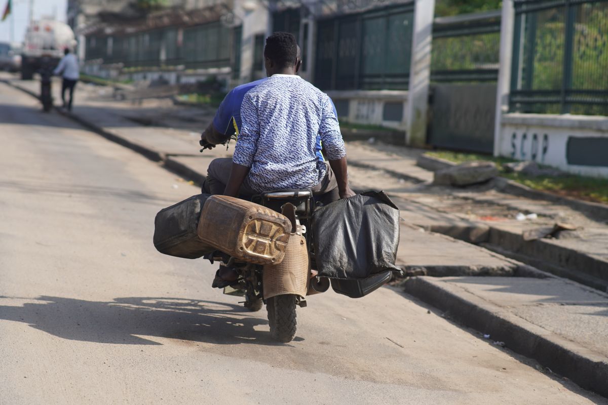 Un homme pousse sa moto chargée de bagages dans une rue de Douala