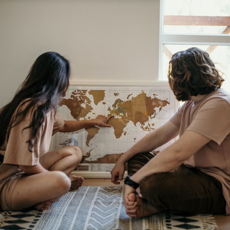 Un couple regarde une carte du monde en souriant